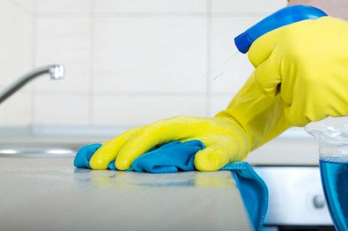 Trained cleaner using safe methods and PPE while cleaning an interior surface