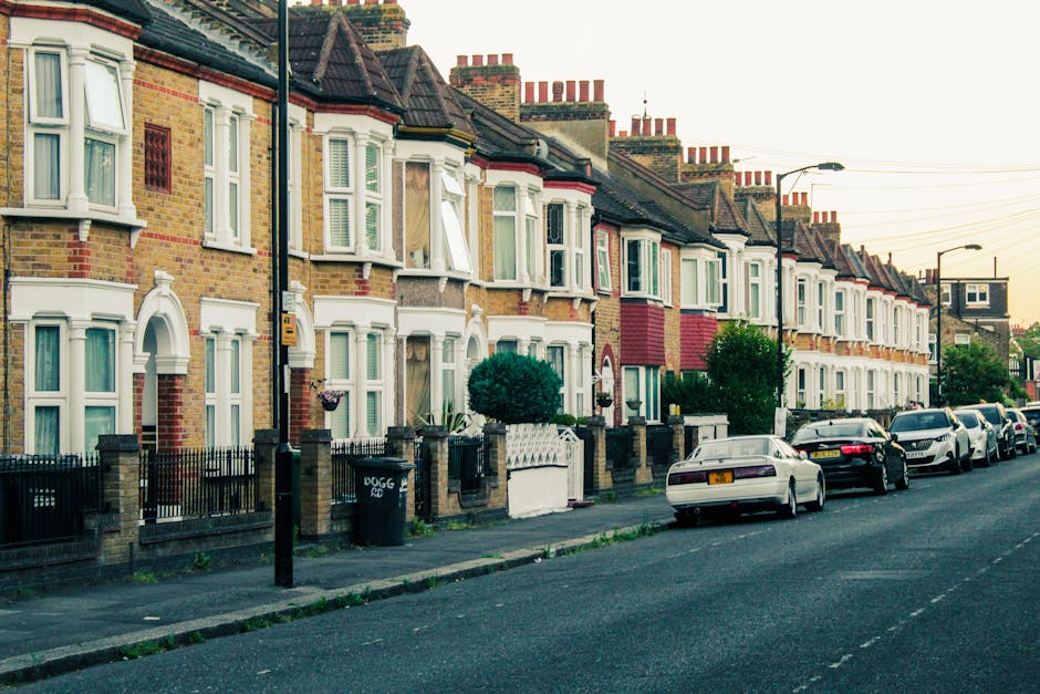 A row of Victorian-style terraced houses with brick facades, white window frames, and decorative bay windows along a residential street in Stockwell Park Estate. The pavement is clean and well-maintai